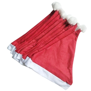 Stack of classic red non-woven Christmas hats with white plush trim and fuzzy pom-poms