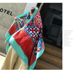 Detail of lightweight bohemian shawl with red and blue floral patterns and mint green border