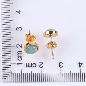 Minimalist gold-plated stud earrings with 10mm light blue stones on a metric ruler