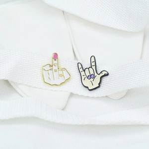 Detailed macro view of two rock hand signs enamel pins with heart icons and colorful nails