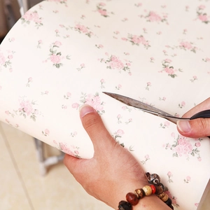 Floral cabinet drawer liner being trimmed with scissors for custom fit