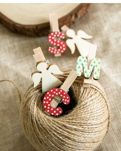 Détail de pinces de Noël en bois avec anges et motifs à pois rouges sur toile de jute