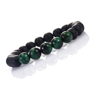Detail of matte black stone bracelet featuring vibrant green tiger eye beads on white base