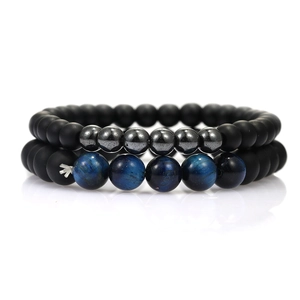Detail view of matte black beads and blue tiger eye stone bracelets on a reflective surface