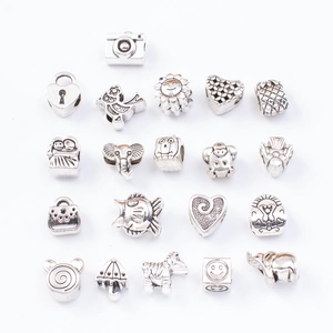 Flat lay of 20 silver DIY charm pendants including elephant bird and heart shapes