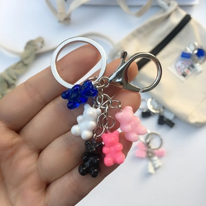 Detail of five colorful resin bears on a silver keychain held in hand for size comparison