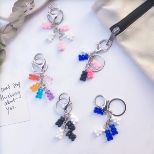 Colorful resin bear keychains in pink, blue and orange shown on a canvas bag background