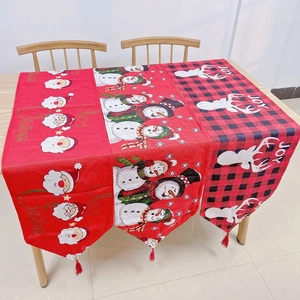 Detail of Christmas table runner with festive Santa and snowman patterns and red tassels