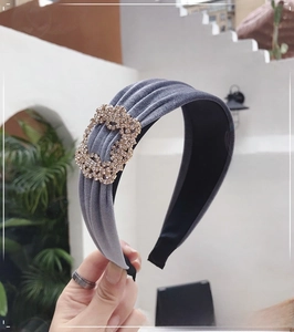 Close-up of blue velvet headband featuring a sparkling rhinestone buckle and pleated texture