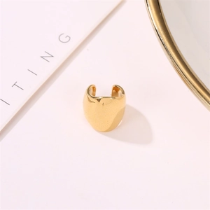 Macro detail of polished wide gold metal ear cuff on a minimalist white background