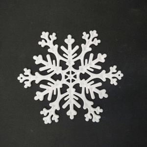 Macro view of white plastic snowflake ornament with intricate hexagonal hollow patterns