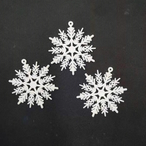 Detailed view of three white plastic snowflake ornaments on a black textured surface