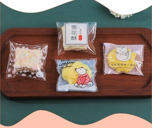 Close-up of clear cookie packaging with cartoon patterns on a dark wooden tray