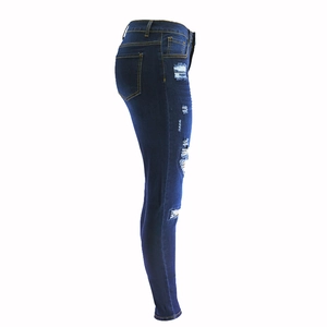 Detail view of dark blue distressed skinny jeans with ripped knees and frayed edges