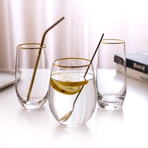 Elegant gold-rimmed egg-shaped crystal glass cup with lemon and straw for stylish dining