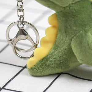 Close-up of green plush dinosaur tail with yellow fins and silver metal keychain