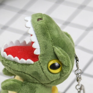 Macro shot of green plush T-Rex keychain with yellow eyes and soft velvet texture