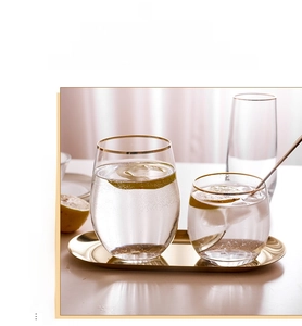 Macro view of gold rimmed hammered glass cups on a luxurious golden oval tray