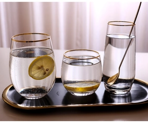 Detailed view of elegant gold-rimmed crystal glass cups in three sizes with a metal spoon