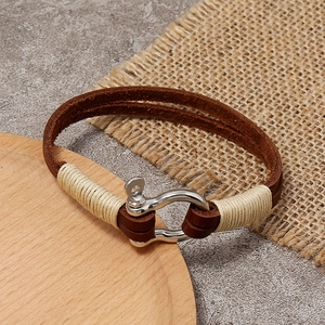 Handcrafted brown leather bracelet with metal horseshoe clasp on a rustic wooden tray