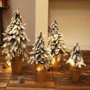 Snow-flocked mini Christmas trees with warm LED lights and kraft paper wrapped bases