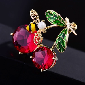 Detail of red crystal cherry brooch with enamel green leaves and gold pearl bee