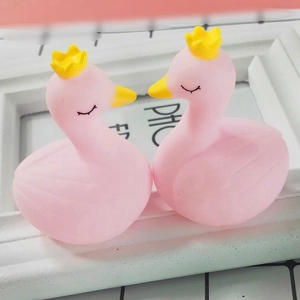 Close-up of pink resin swan figurines with yellow crowns and matte finish texture