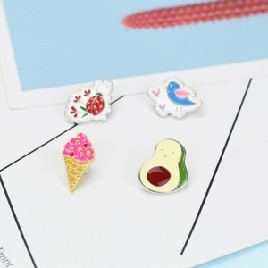 Dettaglio di set di spille smaltate colorate con avocado, gelato e simpatica coccinella