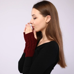 Close-up of wine red cable knit fingerless gloves showing warm textured pattern