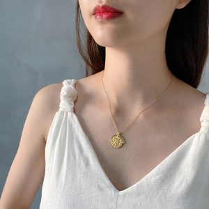 Close-up of golden baroque coin necklace worn on neckline with detailed relief pendant