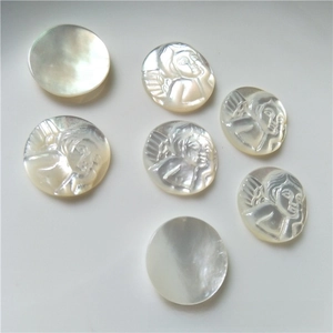 Macro detail of natural mother of pearl shell charms with angel relief carvings