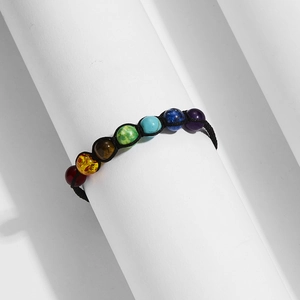Macro shot of 7 chakra natural stone beads on a black braided adjustable cord bracelet