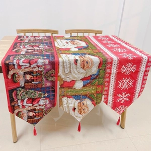 Detailed view of Christmas table runners with Santa patterns and red tassel edges