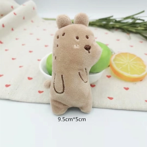 Detailed view of a small brown plush bear brooch inside a white bowl with scale dimensions