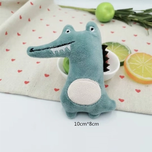 Detailed view of plush crocodile doll accessory measuring 10x8cm on heart patterned cloth