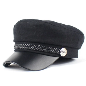 Detail of black tweed newsboy cap with PU leather brim and silver metal button detail