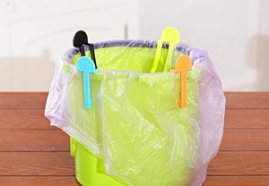 Close-up of colorful non-slip clips fixing a garbage bag to the edge of a plastic bin