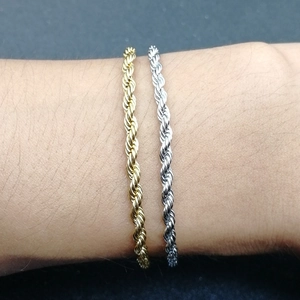 Detail of twisted rope chain bracelets in gold and silver finish on wrist