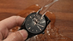 Close-up of waterproof watch under running water showing dual calendar and black leather strap