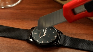 Close-up of scratch-resistant test on black DEDIMA men's quartz mesh band watch