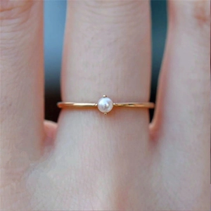 Minimalist 18k gold plated slim ring with a round white pearl on a female finger