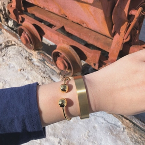Close-up of 18K gold plated bangle set with minimalist metal ball and matte finish texture