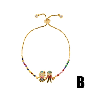 Détail du bracelet en chaîne dorée avec breloques enfants en zircon coloré et fermoir ajustable