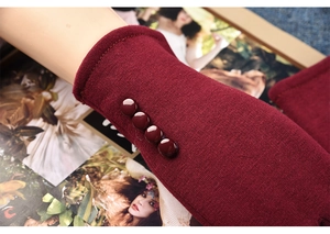 Close-up of wine red knit gloves featuring four vintage buttons on the ribbed cuff