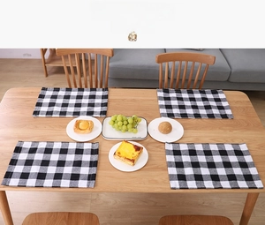 Set of four black and white buffalo plaid placemats on a rustic wooden dining table