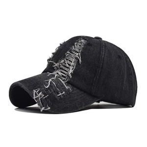 Close-up of distressed vintage black washed cotton baseball cap with ripped brim detail