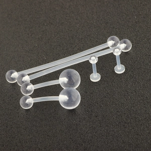 Detail of 6 transparent acrylic body jewelry pieces including barbells on textured foam
