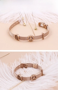 Nahaufnahme von roségoldenem Mesh-Armband mit Schmetterlings- und Friedenszeichen-Anhängern