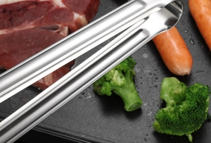 Gros plan d'une pince en inox ramassant du steak et du brocoli sur un grill chaud