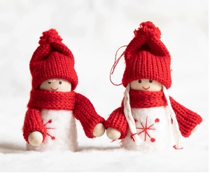 Close-up of wooden Christmas angel figurines with red knit hats and white wool bodies